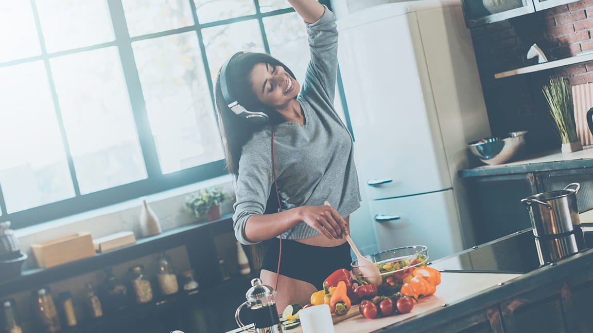 woman wearing headphones makes breakfast and dances