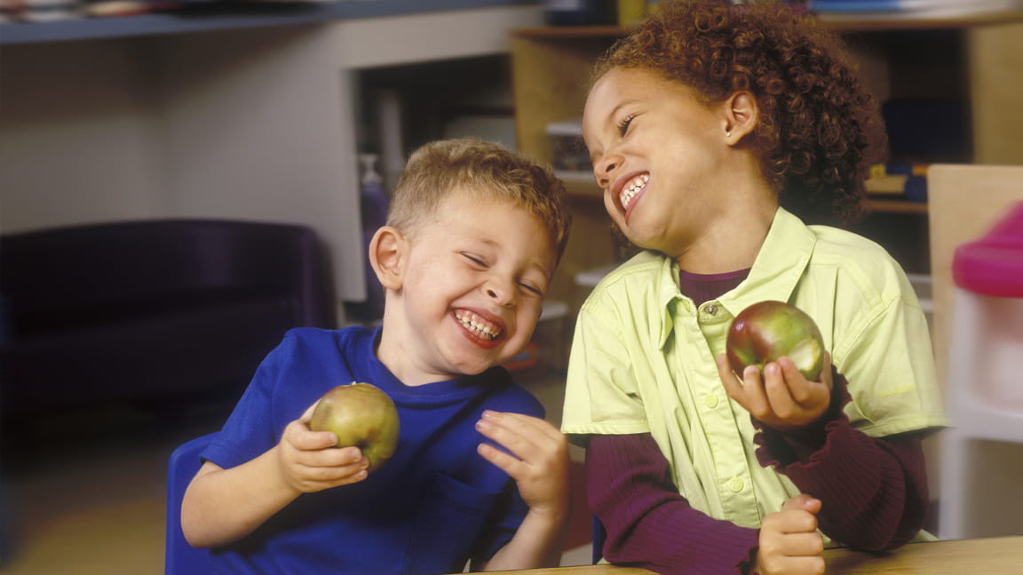 niños riendo mientras comen manzanas