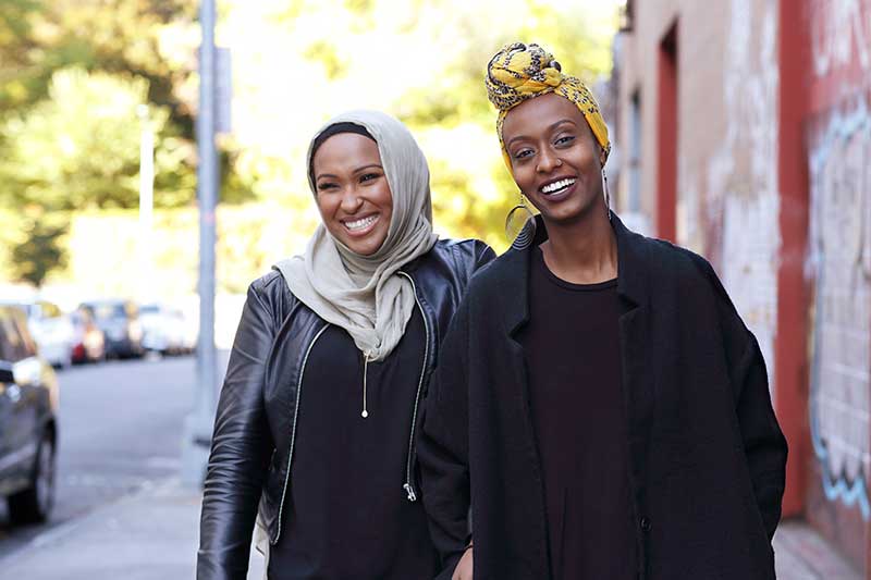 two women walking down city sidewalk