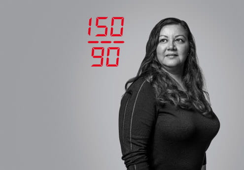 Woman in black and white photo her blood pressure is on the image in red font reading 150/90