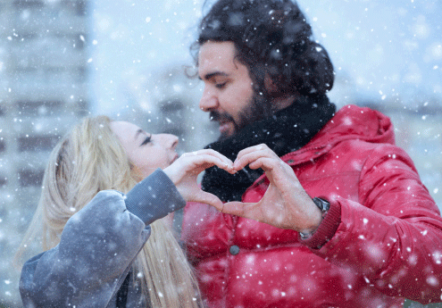 Couple making hearts with their hands in the snow