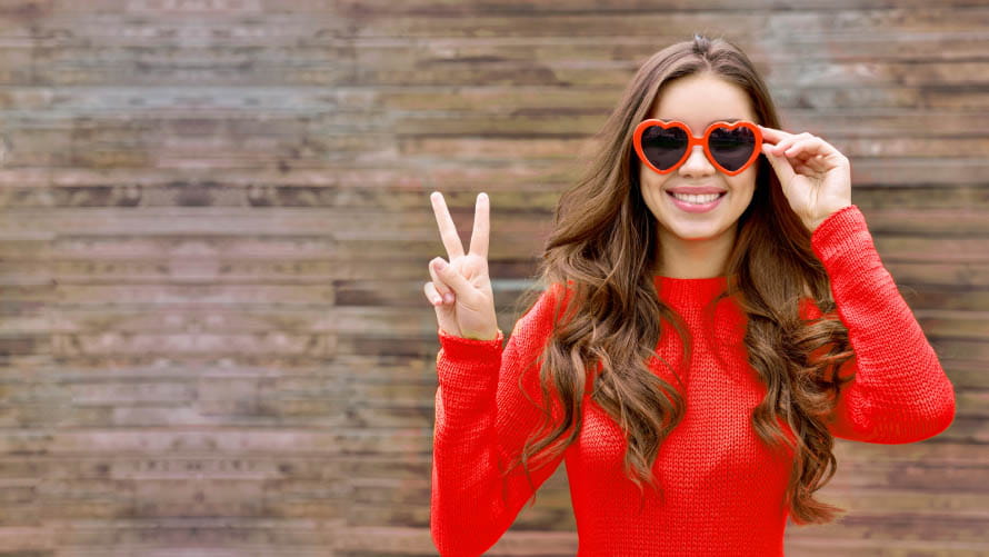 women in red heart sunglasses holding up her hand with the piece sign