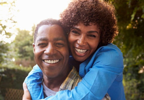 portrait of happy woman hugs husband from behind