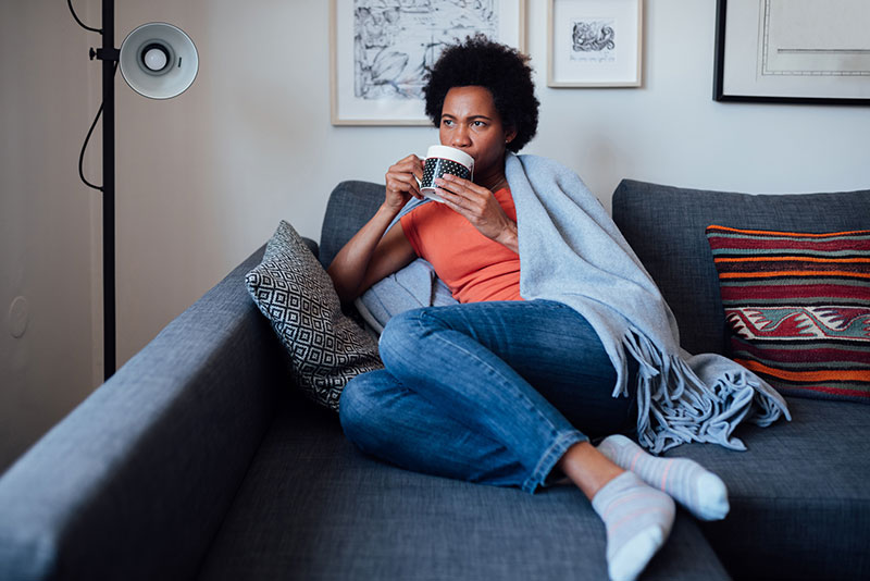 sick woman drinking on couch