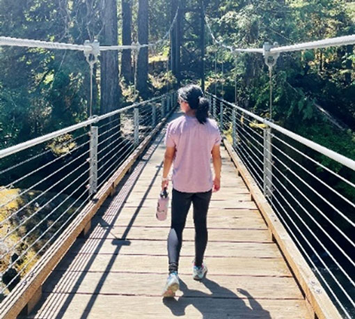 Real Women Class 2023 Jia Wu walking over a bridge