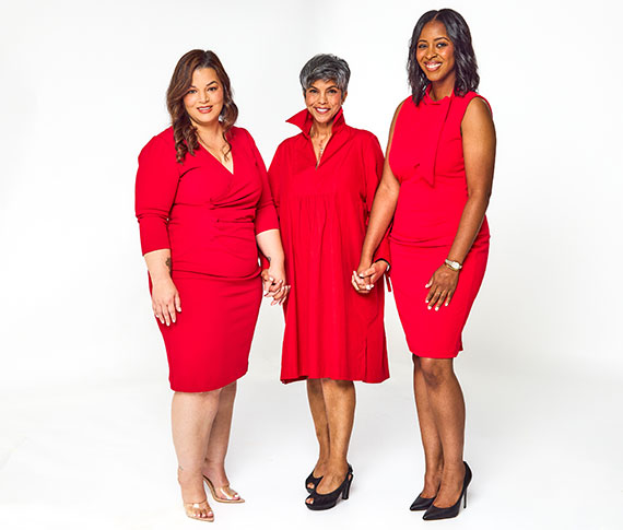 Three women from the 2024 Class of Real Women all wearing red and holding hands