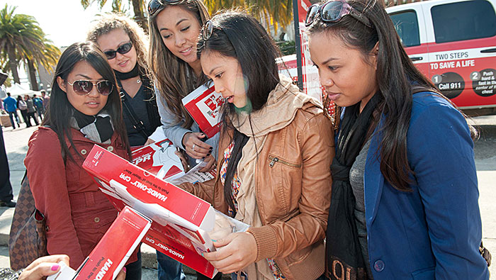 women reading Hands-Only CPR Kit box