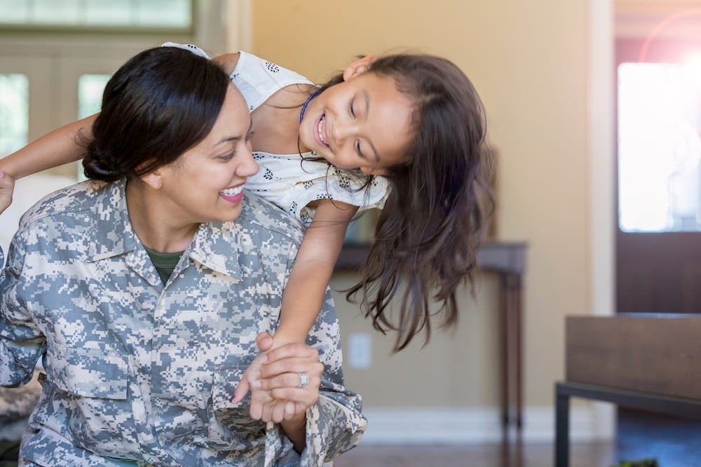 Young Hispanic woman in the military with young girl smiling