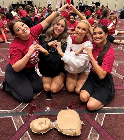 Women making heart hands and learning CPR