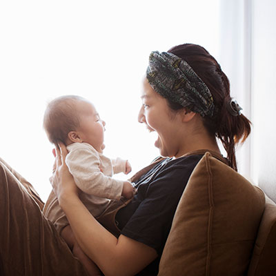 Mom and baby laugh face to face at home