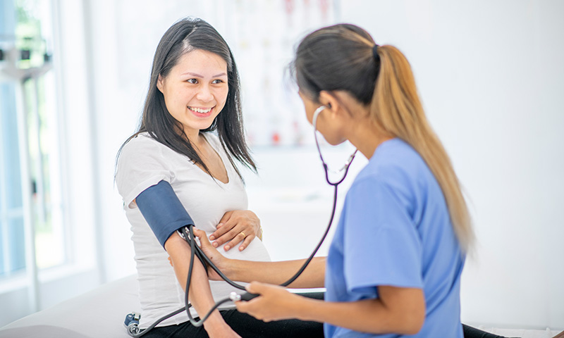 nurse checks pregnant woman's blood pressure