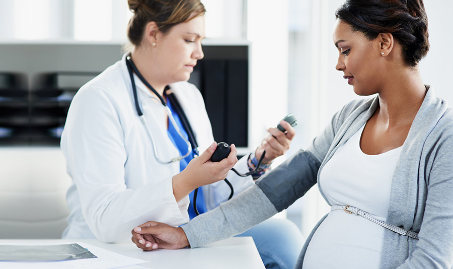 médico toma la presión arterial de la paciente embarazada