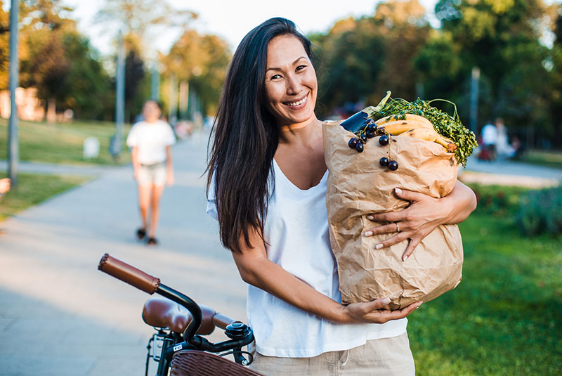 mujer de mediana edad que lleva una bolsa de alimentos en una bicicleta