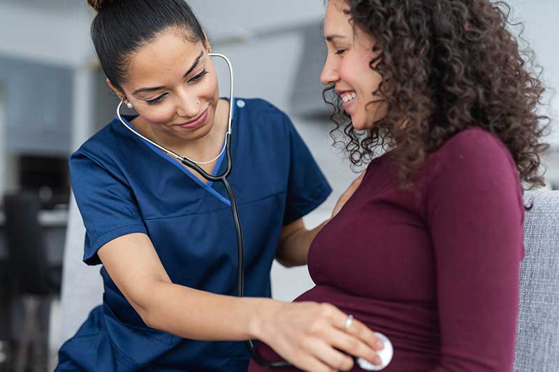 doctor with stethoscope on pregnant mom's belly