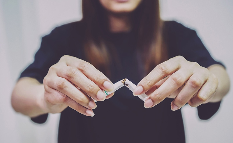 mujer rompiendo un cigarrillo por la mitad