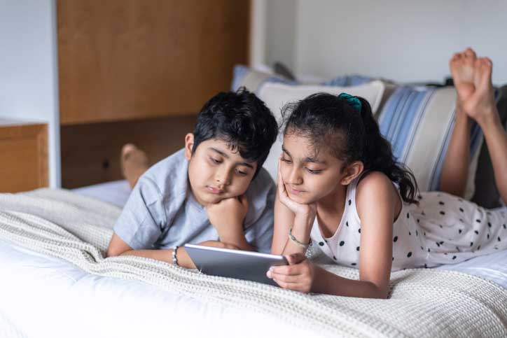 Un niño y una niña de primaria miran un video en una tableta