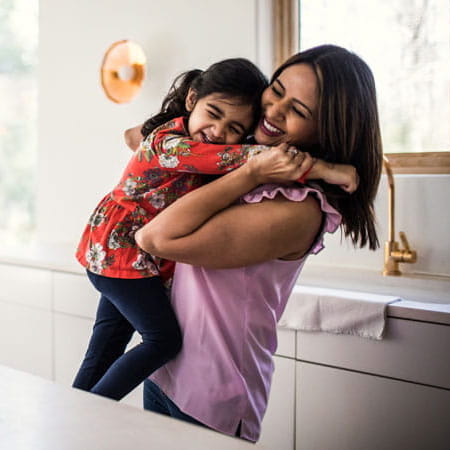 Mother and daughter embracing in the kitchen.