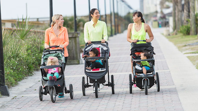 Three mothers walking with their babies in strollers