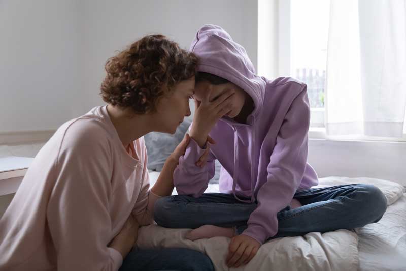 Teen looking stressed with mom trying to comfort her