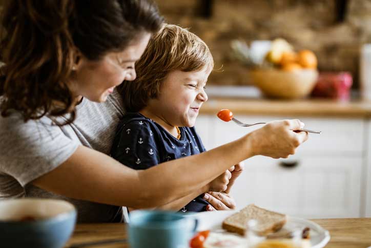 Madre intentando alimentar a un niño delicado para comer