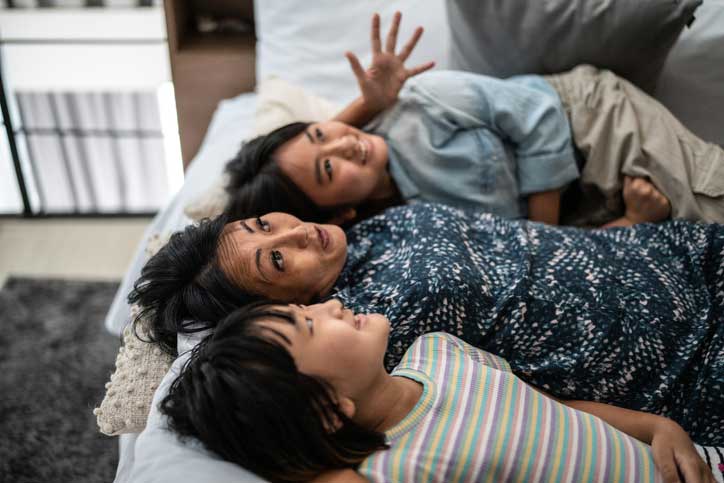 Madre contando historias a sus hijos en la cama en casa