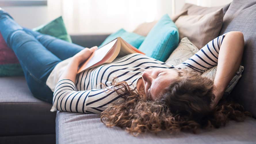 Woman with book relaxing on couch