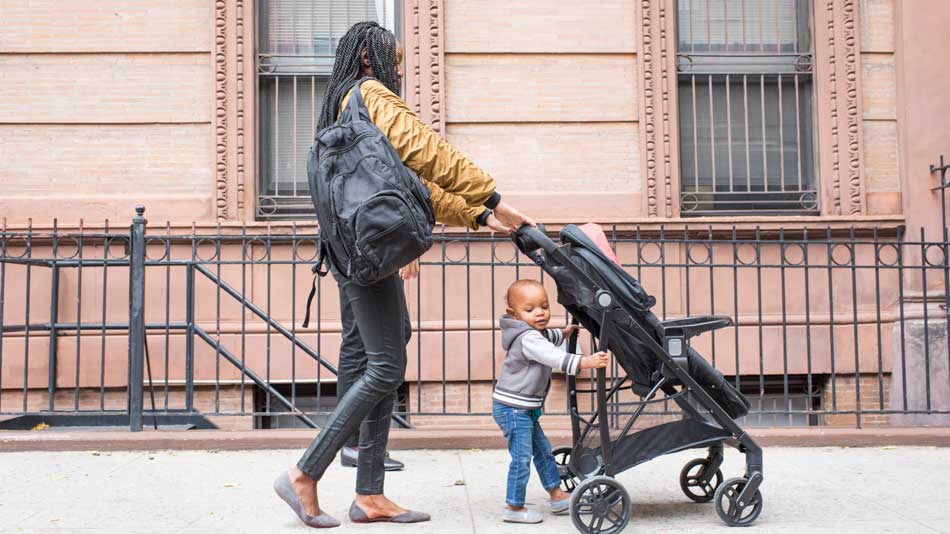 Madre joven caminando con su hija pequeña en la ciudad