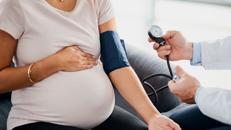 un médico que mide la presión arterial de una mujer embarazada