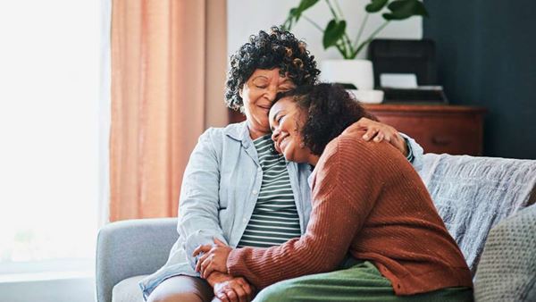 mujer de edad avanzada que se relaja con su hija en el sofá de su casa