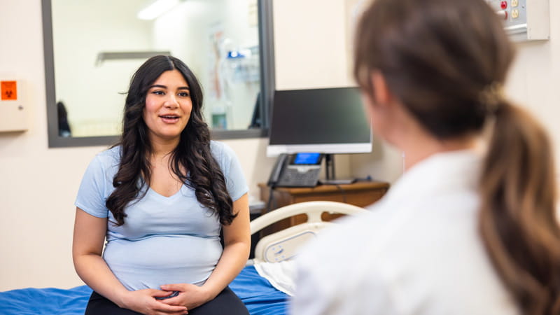 Young pregnant female talking with her female doctor at a checkup. 