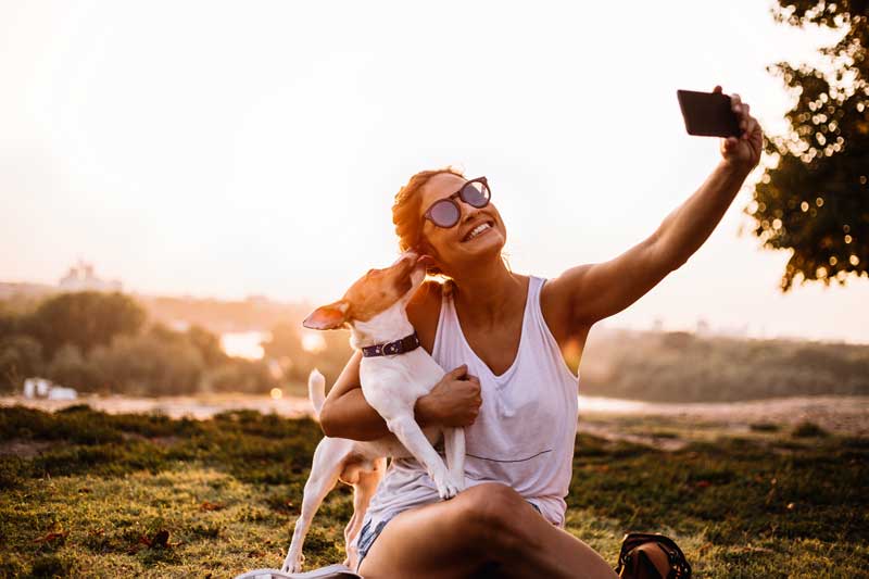 women and dog taking a selfie in a park