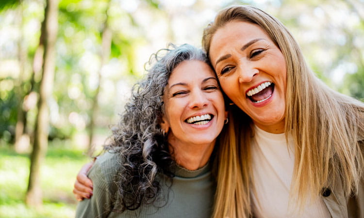 Two mature women embracing outside and laughing