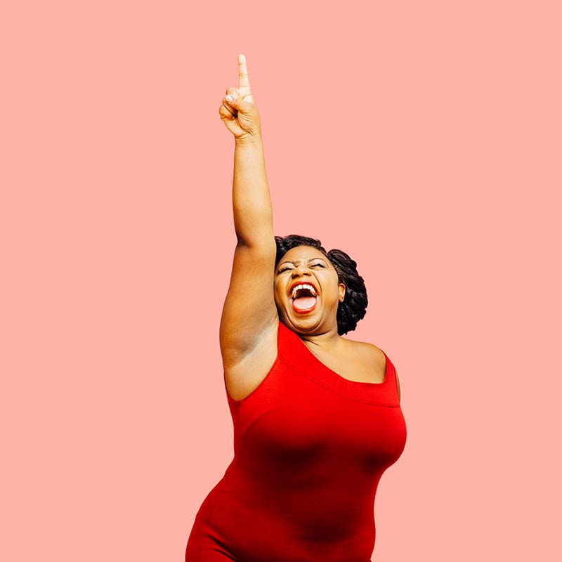 Enthusiastic woman in red dress disco dancing, pointing straight up