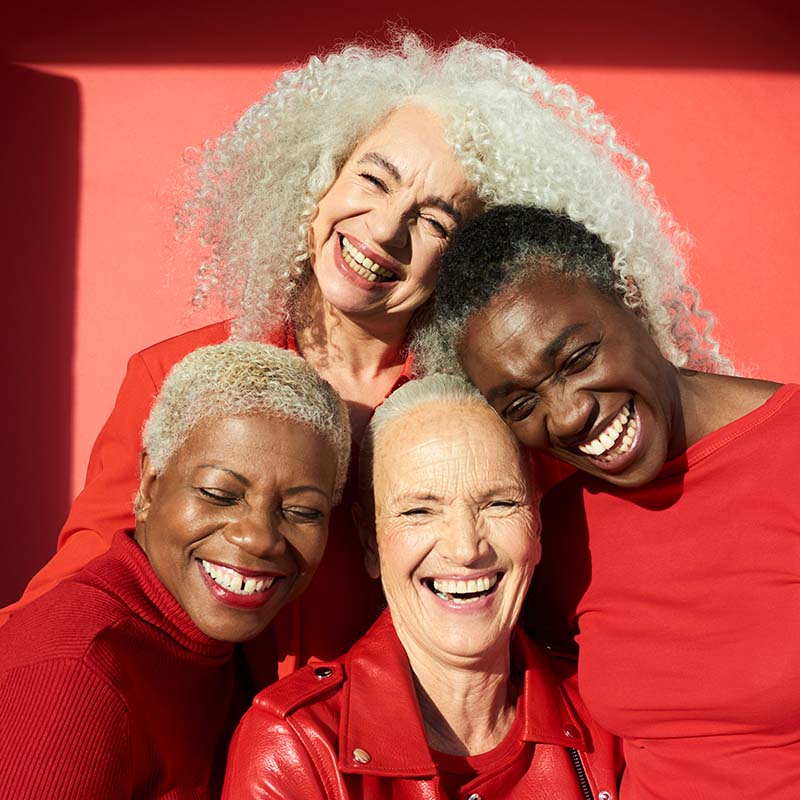 Grupo de mujeres sonrientes que se ríen vestidas de rojo
