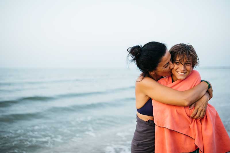mom hugging son at the beach