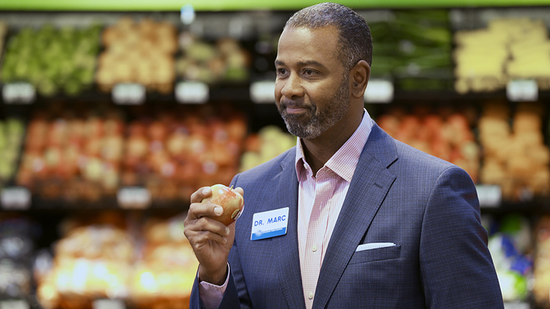 El Dr. Marc Watkins sostiene una manzana en un supermercado