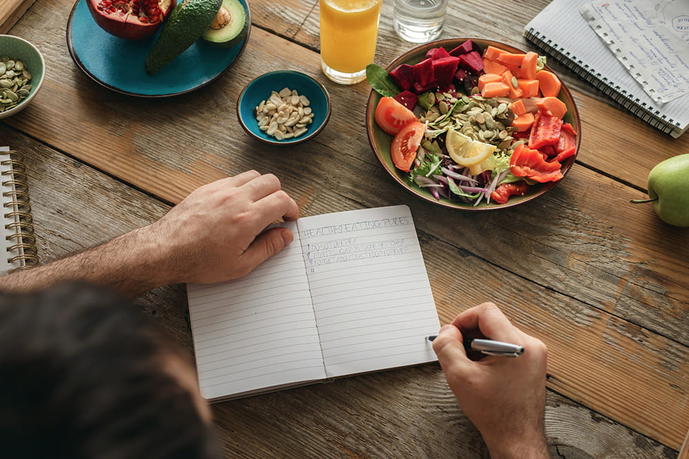 hombre planificando comidas en una mesa con comida