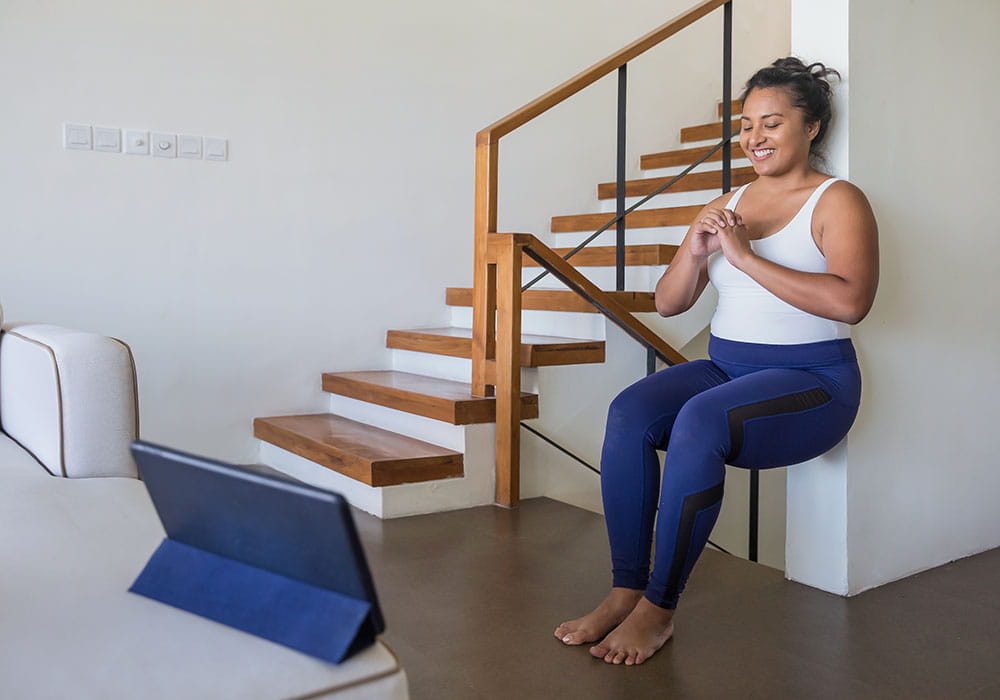 Mujer practicando sentadillas contra una pared en casa