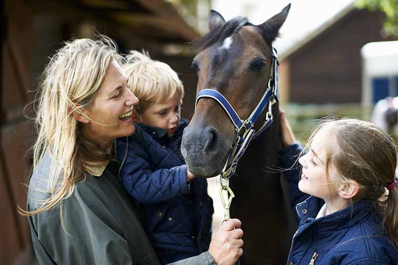 Mature woman with son and daughter petting horse 