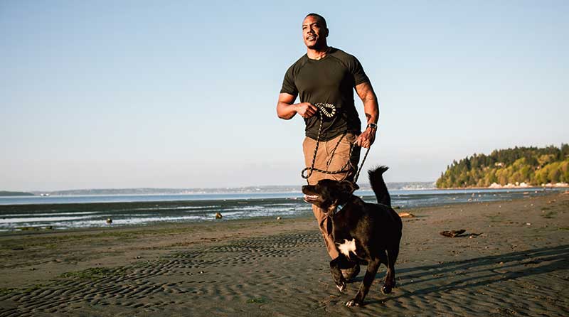 hombre corriendo con su perro en la playa