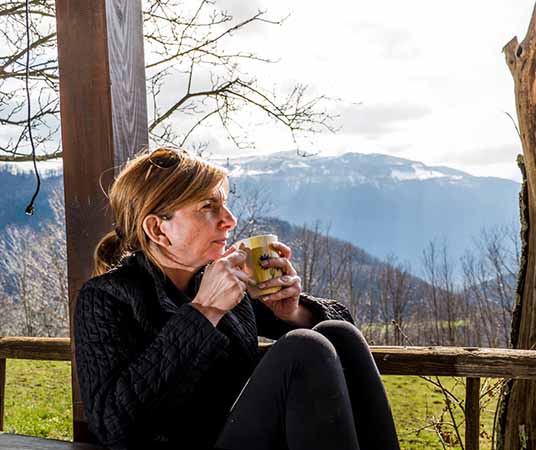 Mujeres maduras bebiendo café en el porche con montañas en el fondo