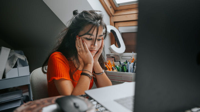 mujer adolescente que se siente estresada estudiando en casa