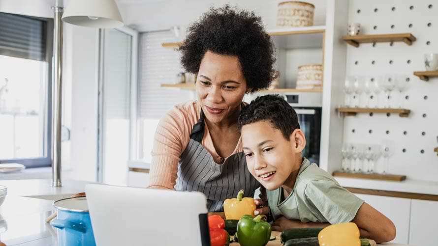 Un niño y su madre en la cocina preparando la comida siguiendo una receta en una tableta