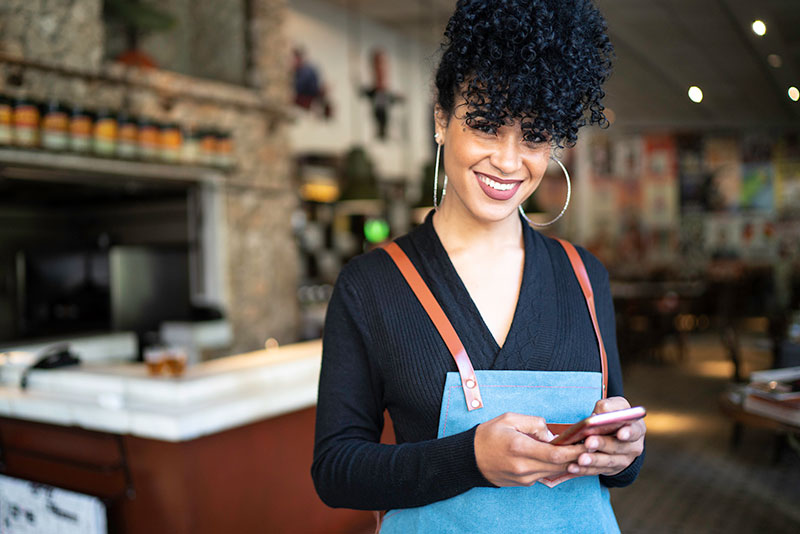 una mujer que trabaja en un restaurante utiliza un teléfono celular una mujer que trabaja en un restaurante utiliza un teléfono celular