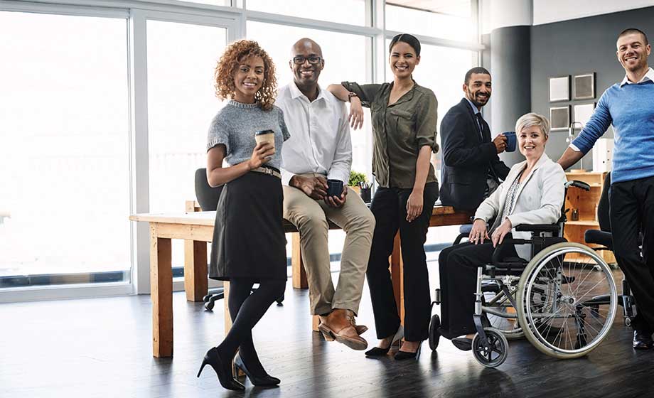 group of diverse people in a work environment posing for photo while smiling