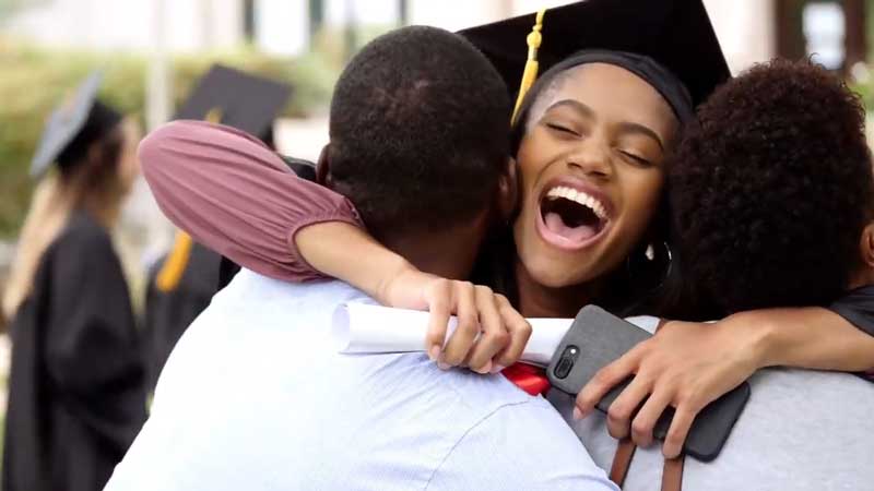 Imagen del video de la vacuna contra el COVID-19 en la que un graduado abraza a sus padres