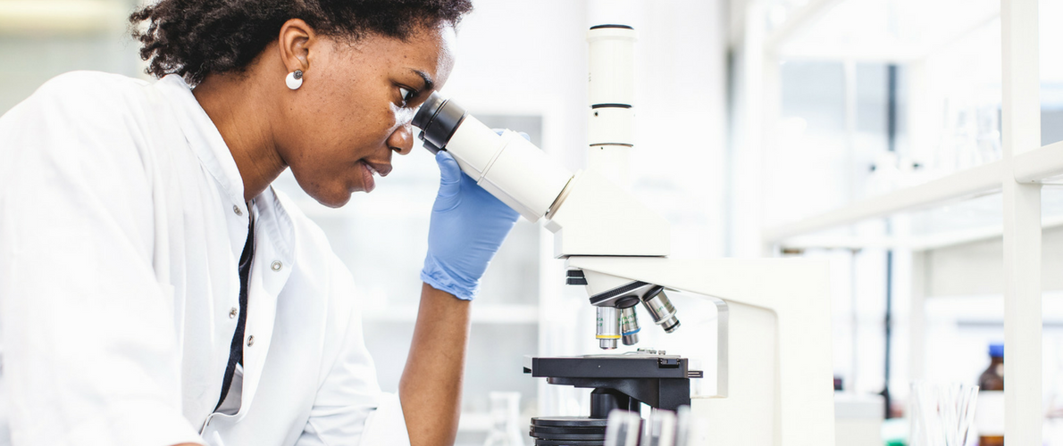 female researcher looking into a microscope