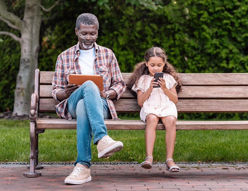 abuelo y niño mirando dispositivos móviles