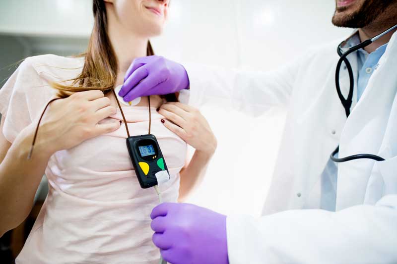 médico colocando un monitor Holter en un paciente