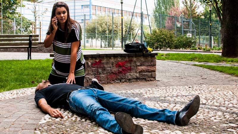 mujer llamando para pedir ayuda para un hombre que está en el suelo